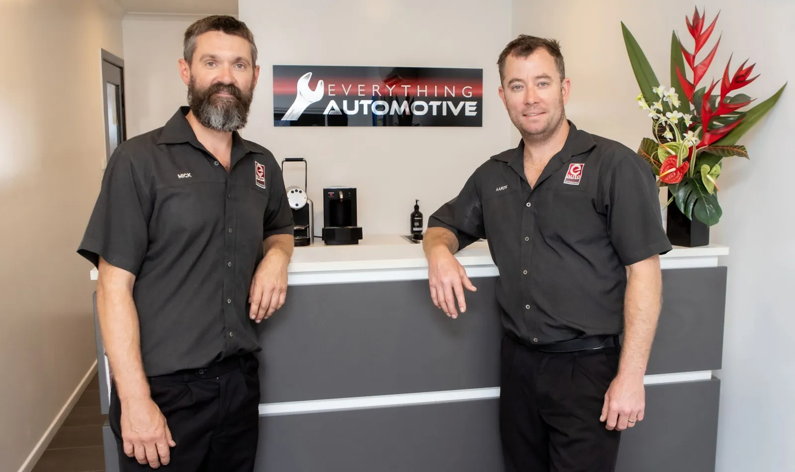 Two uniformed Everything Automotive team members at the workshop's reception counter