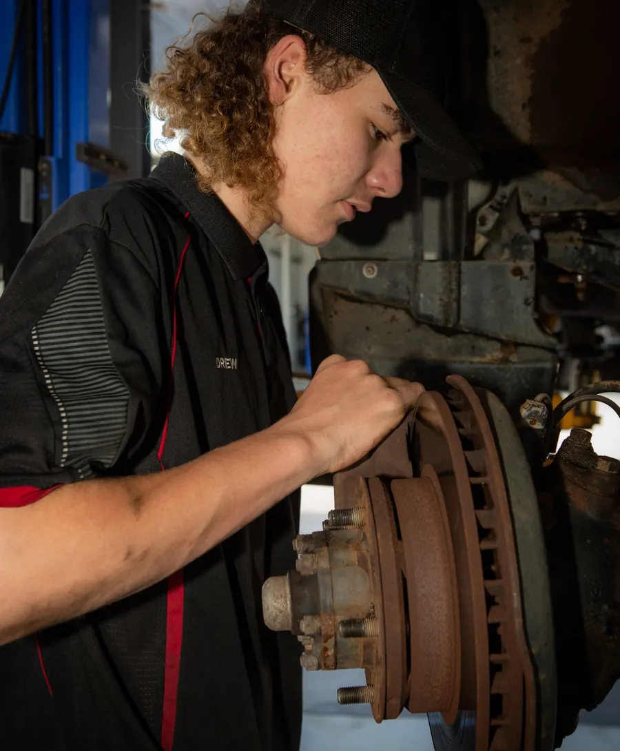 A mechanic working on a brake rotor and hub