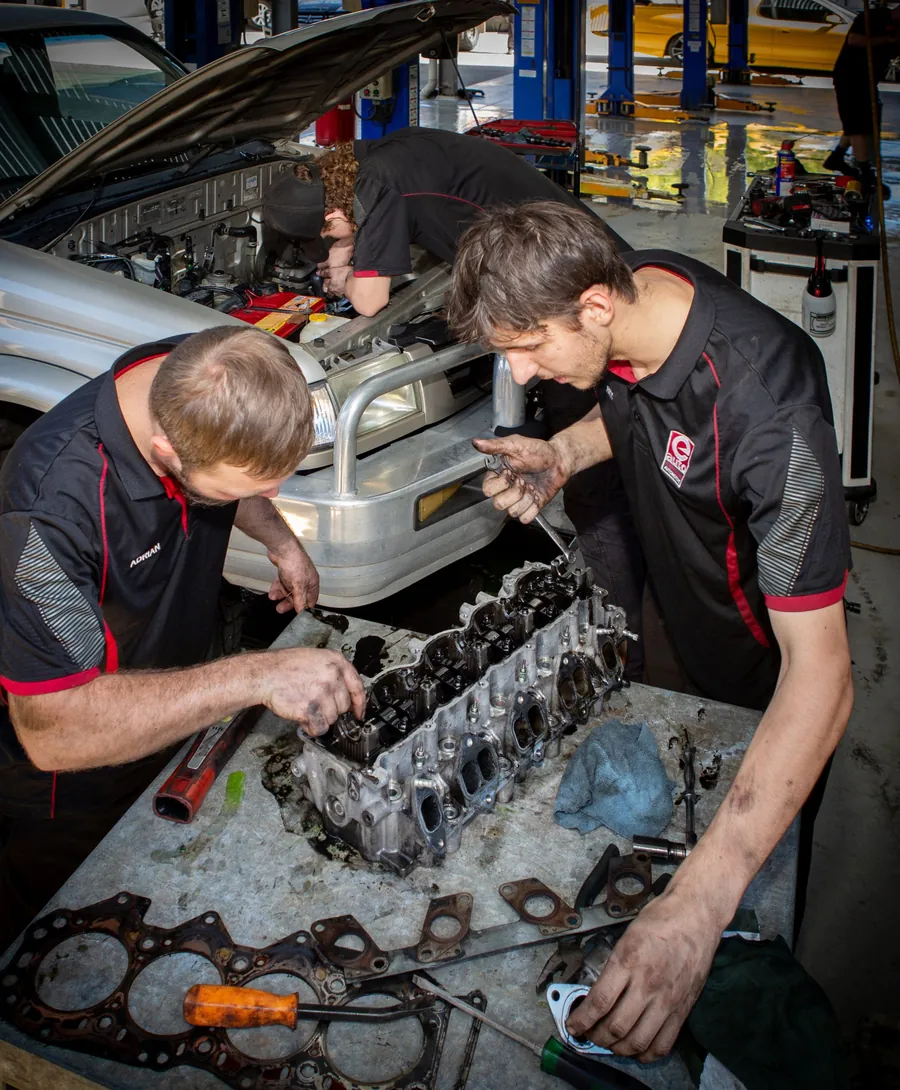 Two mechanics rebuilding an engine head on the workbench