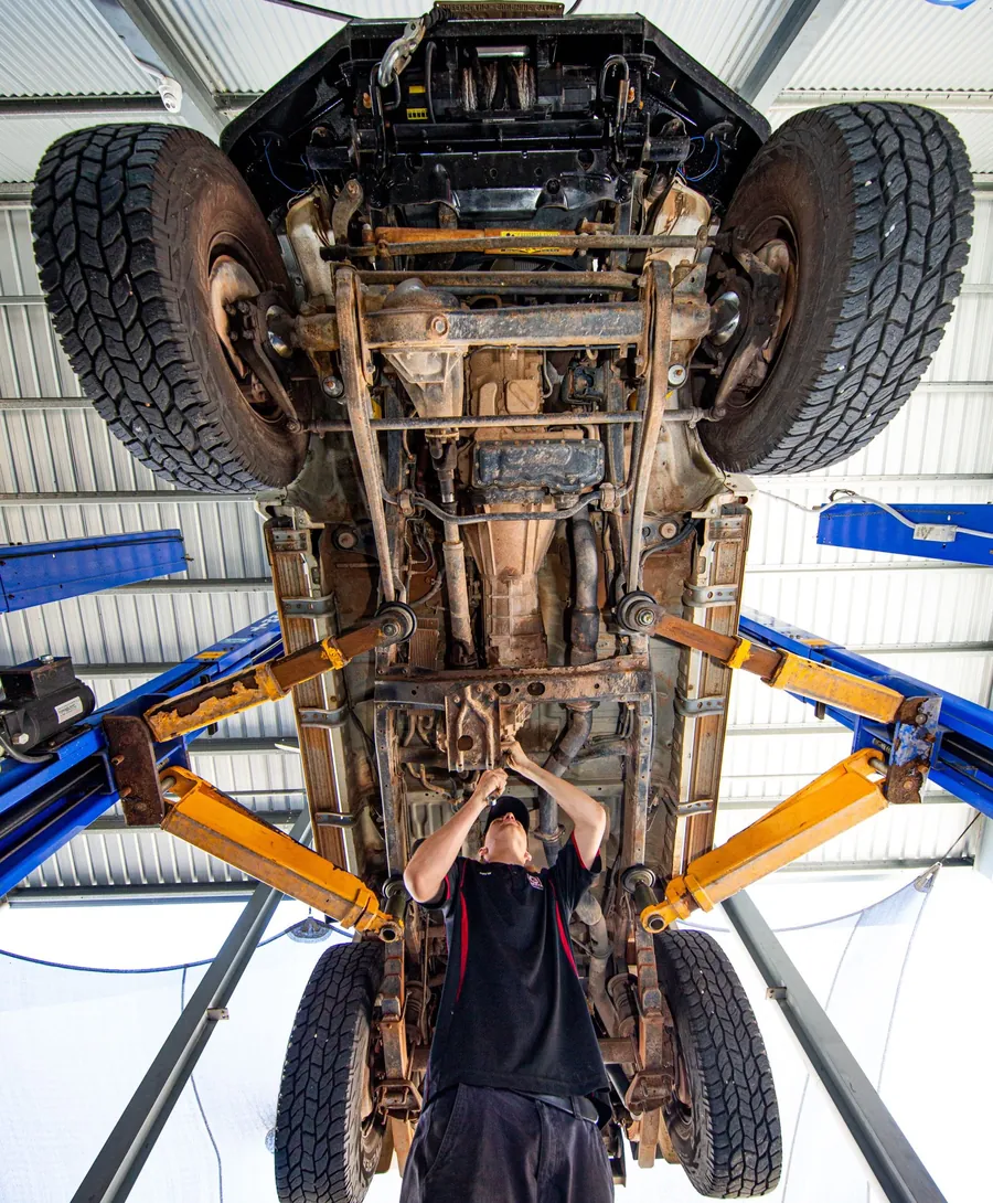 Looking up at the chassis and suspension of a 4WD raised on a hoist