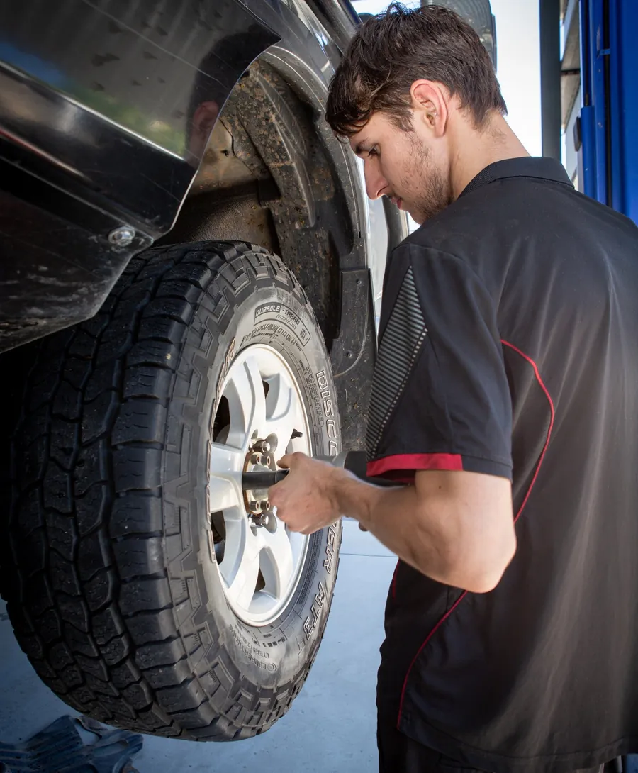 A mechanic tightening the wheel nuts on a 4WD all-terrain tyre